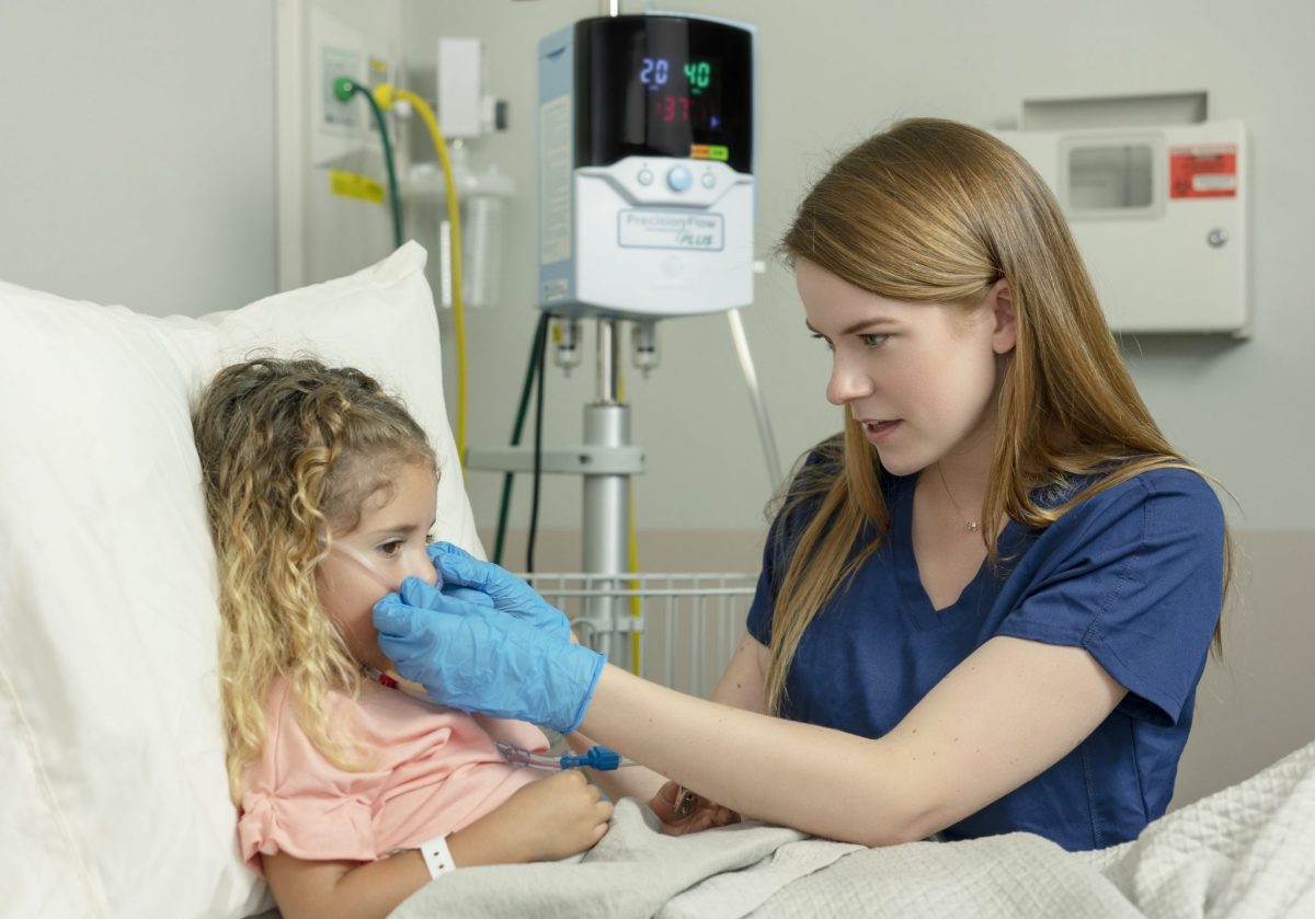 Image of a female clinician putting a Vapotherm cannula on a pediatric patient