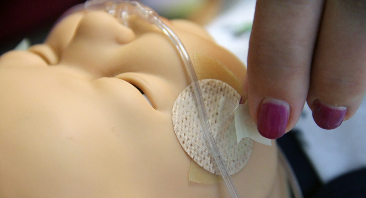 image of a neonatal practice dummy with facial adhesives and cannula