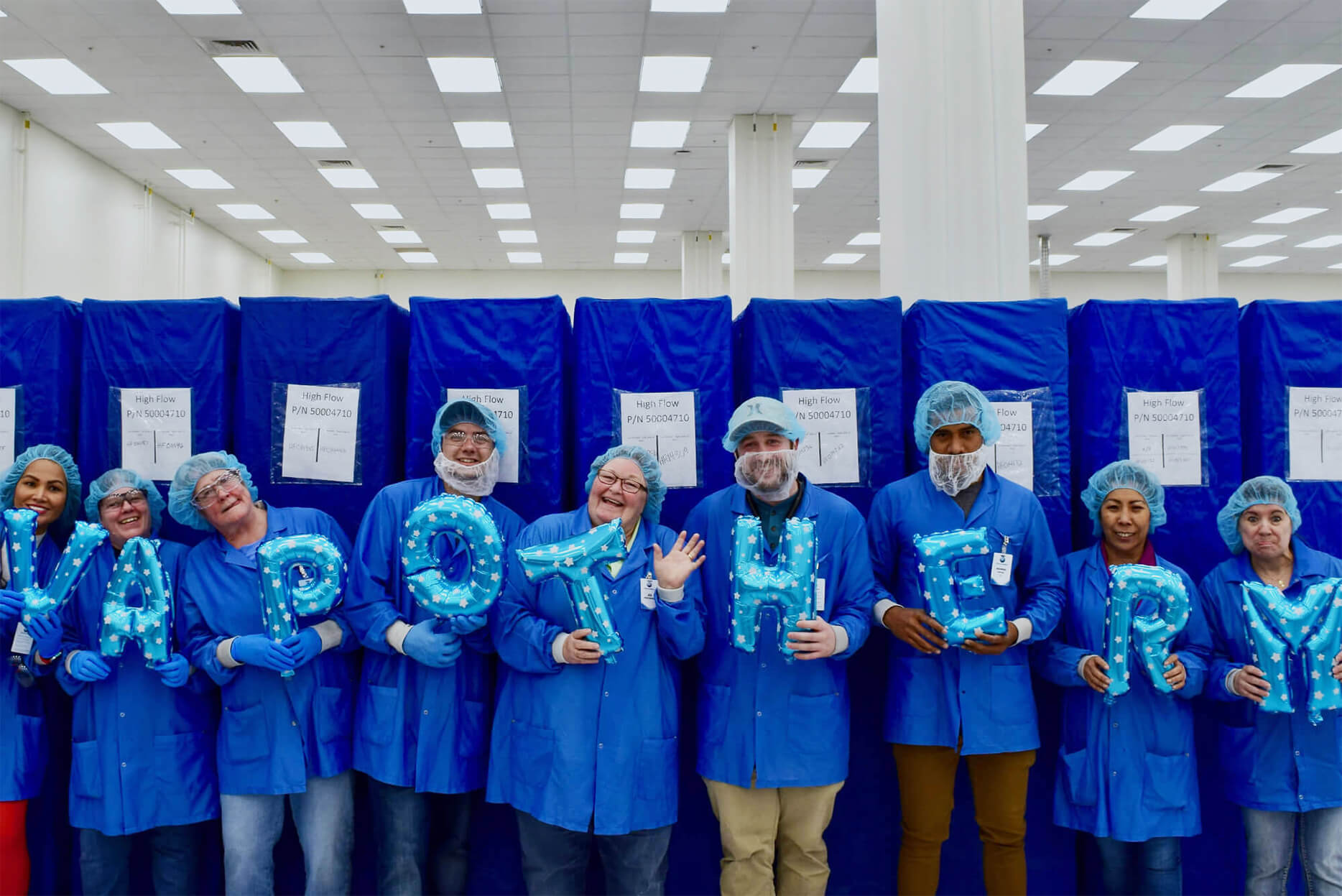 Image of Vapotherm clean room team holding letters that spell out Vapotherm while making silly faces