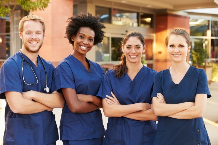 Image of people in scrubs smiling together outside